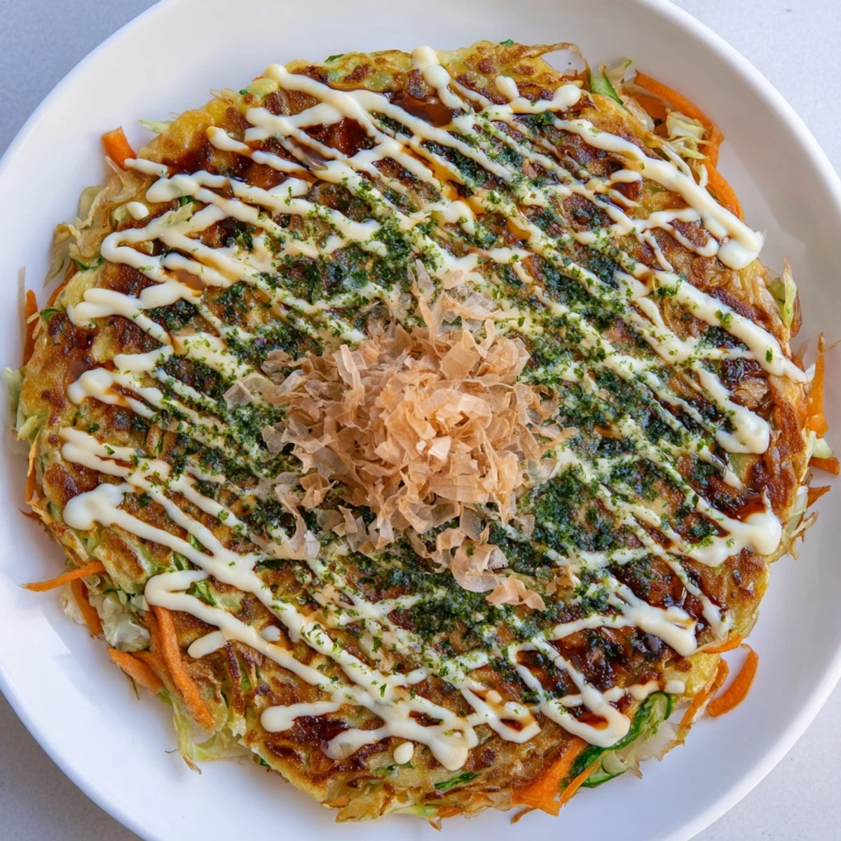 Savory Japanese okonomiyaki pancakes with a delicious mix of cabbage, sauce, and bonito flakes.