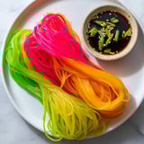 Vibrant swirls of neon-colored Neon Noodle Clouds, a playful appetizer with a unique texture.