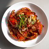 A close-up of glossy Singaporean chili crab, showcasing the spicy, savory, and sweet flavors.