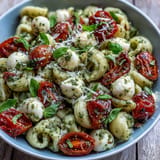 Tender Caprese pasta salad with fragrant basil pesto and fresh mozzarella for lunch.