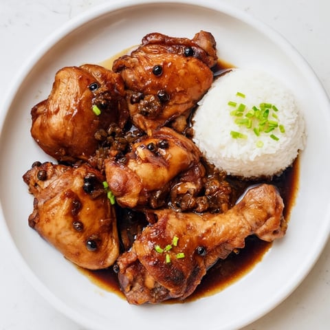 Tender Filipino Chicken Adobo, glistening with sauce and served over fluffy white rice.