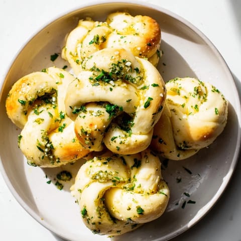 Freshly baked Homemade Garlic Knots glistening from garlic butter, a comforting appetizer you'll love.