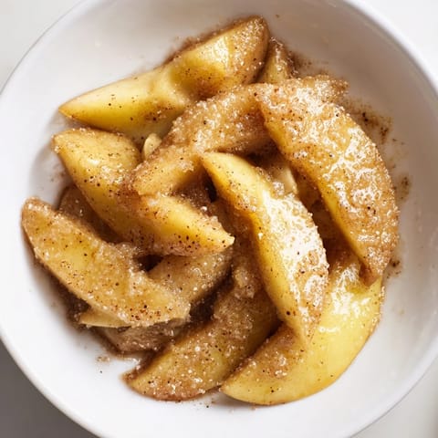 Golden baked apple slices feature a bubbly, cinnamon-infused brown sugar sauce, ready to serve.