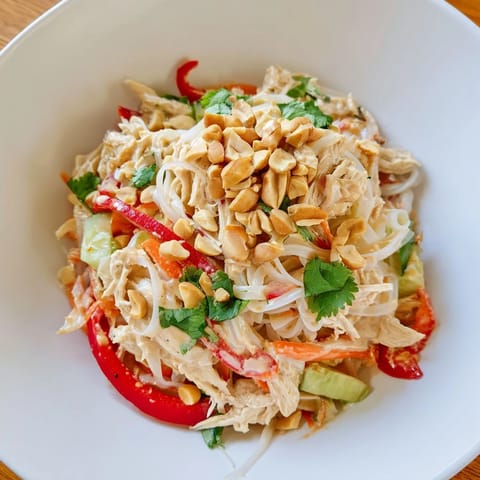 A close-up of Thai-inspired peanut chicken pasta, showcasing creamy dressing and fresh cilantro garnish.