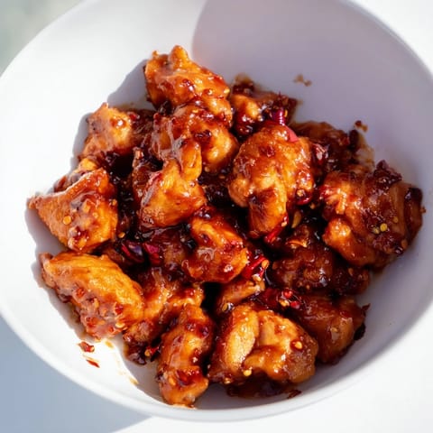 A close-up of the Sweet Chili Chicken Bowl, featuring glossy chicken pieces glistening in a tangy-sweet sauce over steamed rice and vibrant green broccoli.