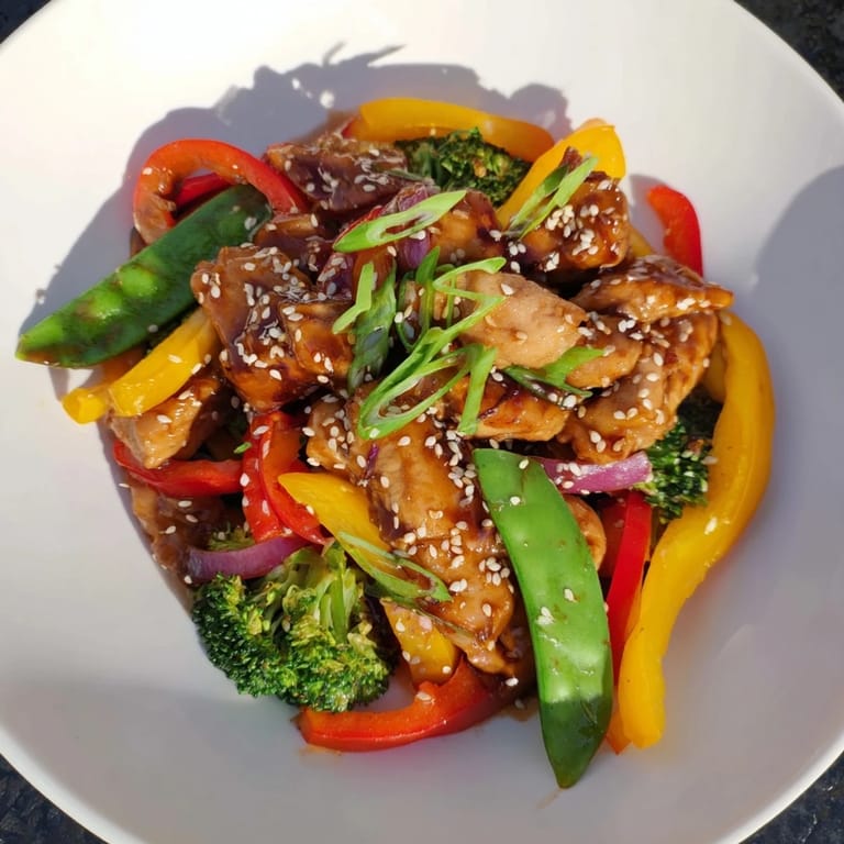 Tender chicken and crisp vegetables in a savory Sheet Pan Chicken Stir-Fry, garnished with sesame seeds.