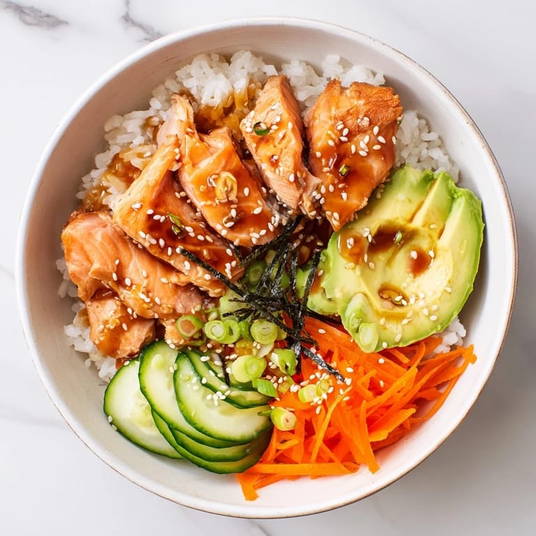 Freshly plated Japanese-Style Salmon & Chicken Rice Bowl loaded with savory salmon, veggies, and sesame seeds, ready to enjoy.