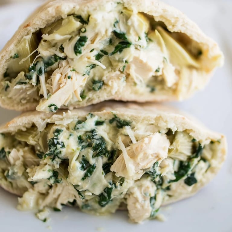 Freshly baked Spinach Artichoke Chicken Stuffed Pita with herbs, served with lemon wedges on a rustic table.