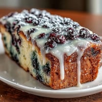 A moist lemon loaf bursting with fresh blueberries and topped with a sweet lemon glaze, perfect for baby showers.